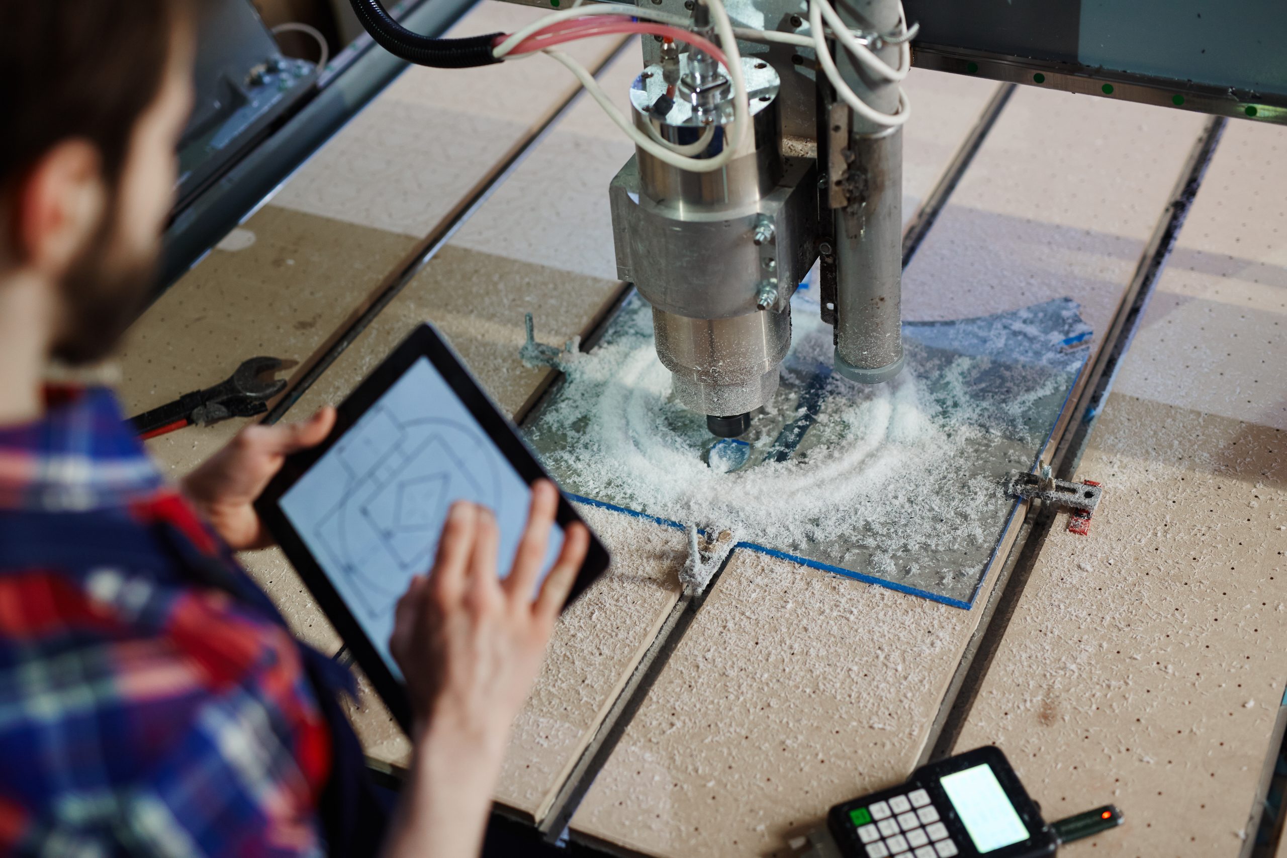 Engineer with touchpad and lathe machine.